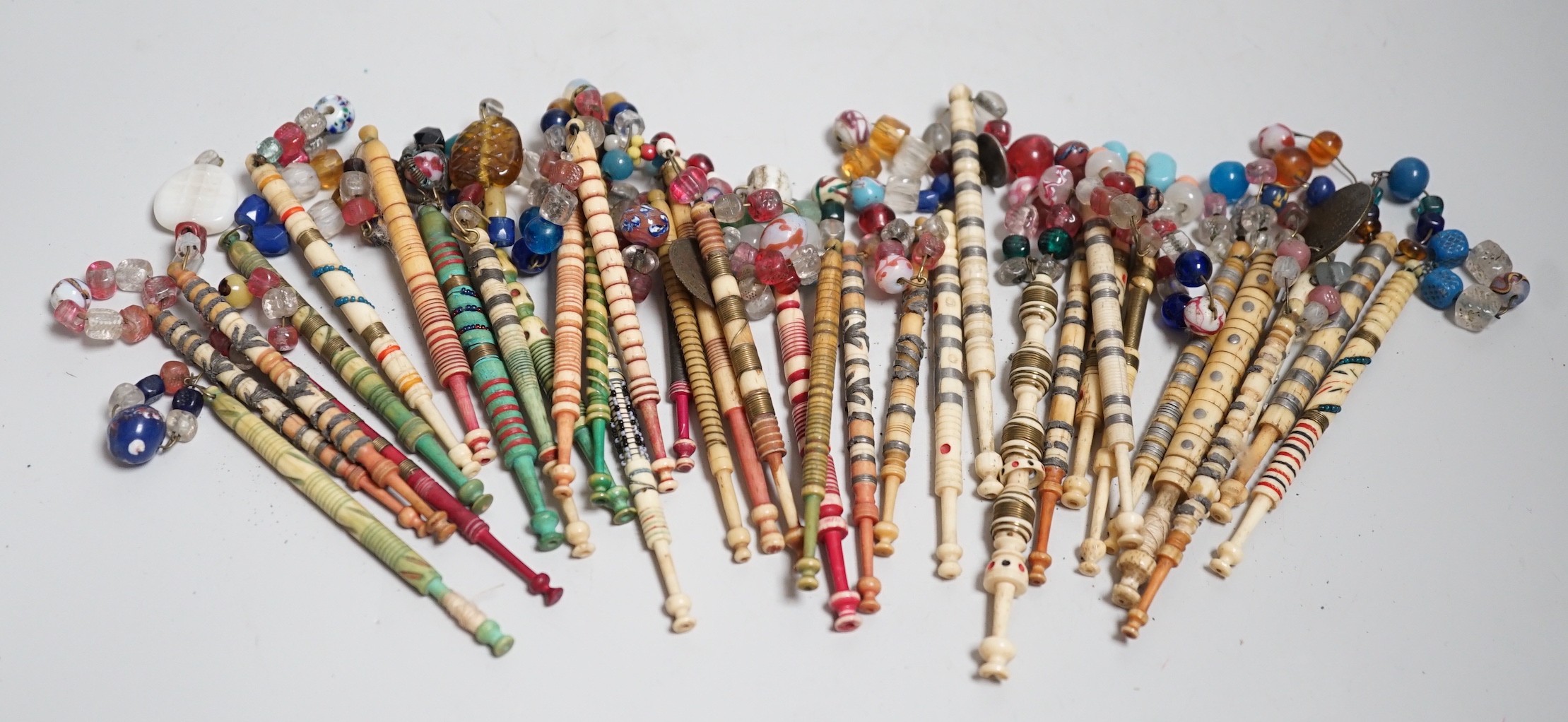 Twenty one 19th century stained and turned bone lace bobbins with glass bead tops and thirteen ornate bone and metal decorated lace bobbins with bead tops (35)